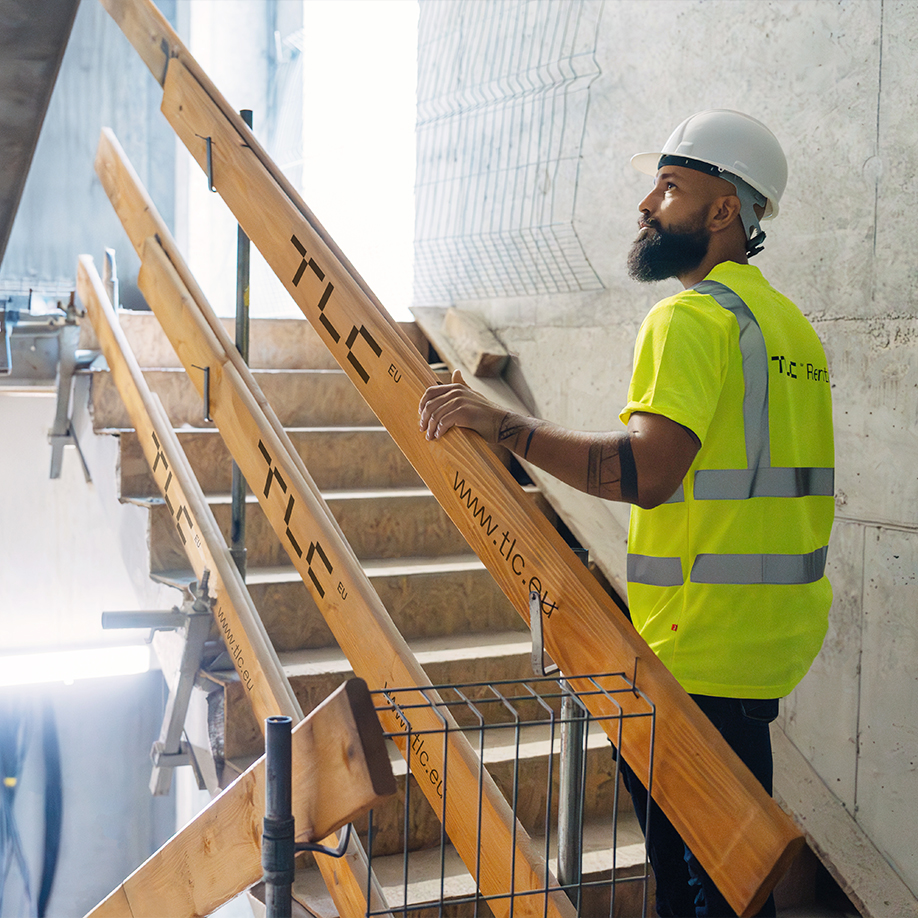 Woman in high-visibility vest standing by metal Mobilt temporary fence panels at a construction site