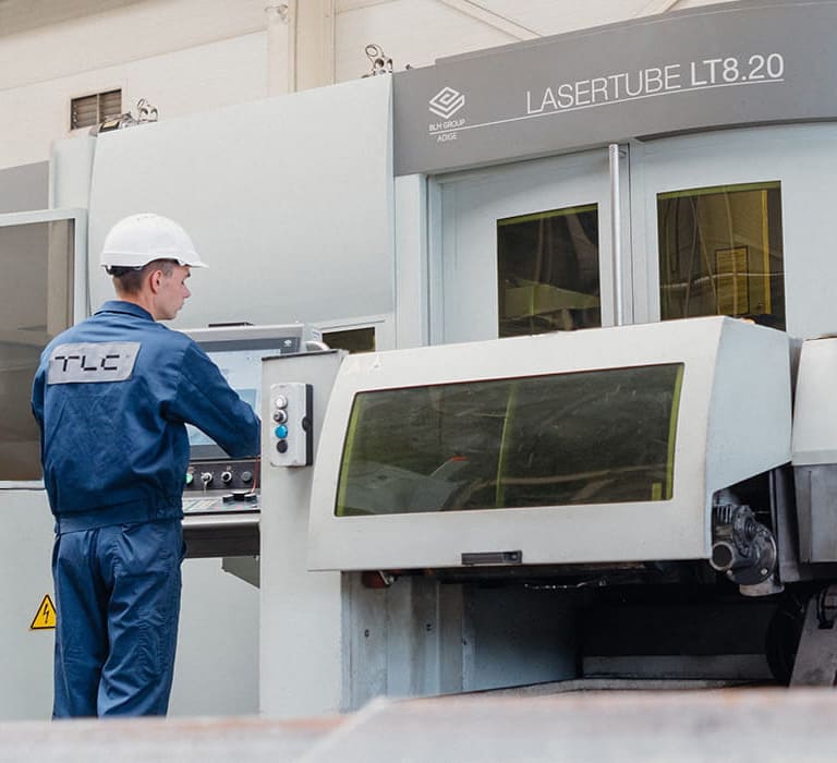 Technician in a blue uniform operating the control panel of  industrial machine.